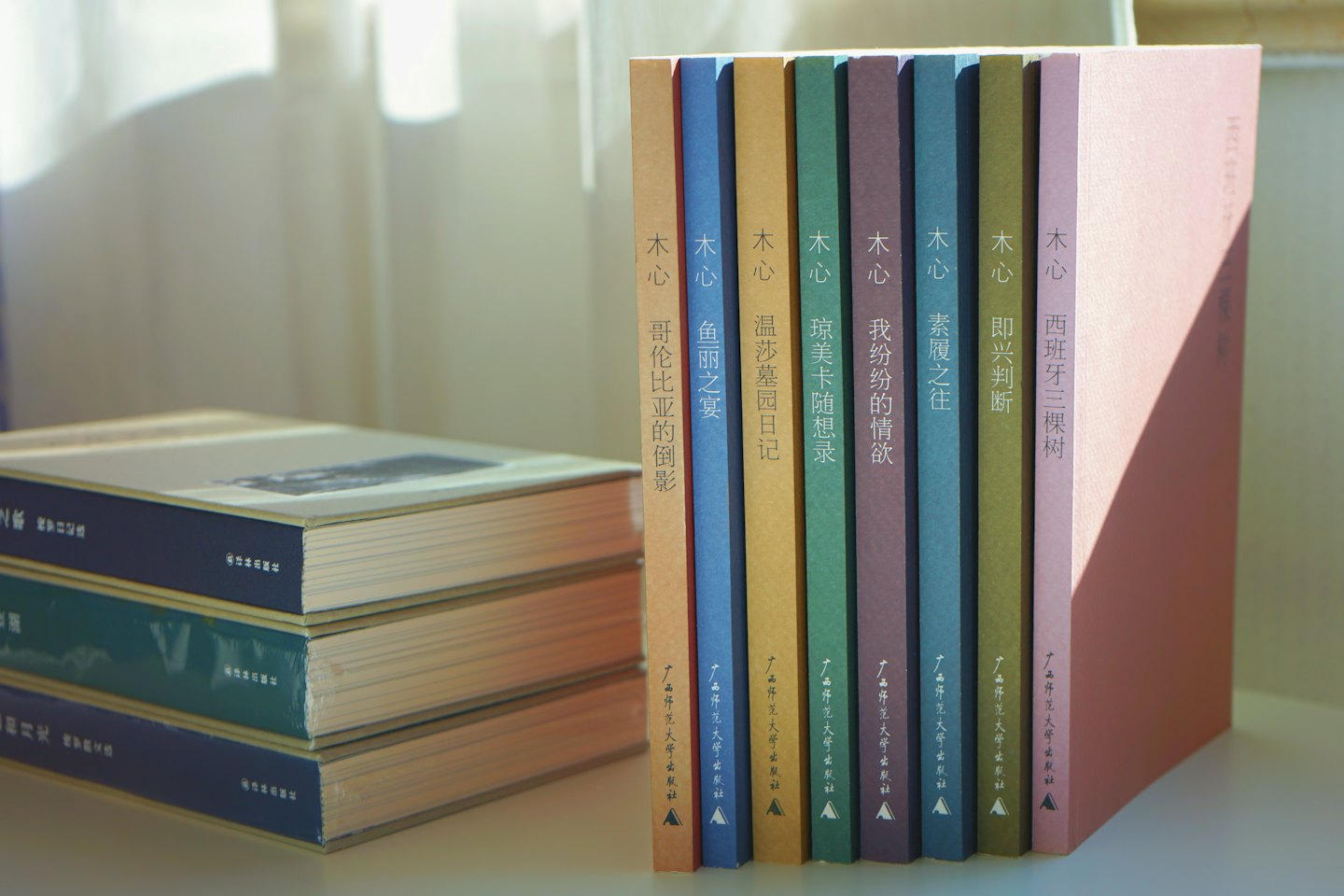 Seven standing books beside a small stack of books.